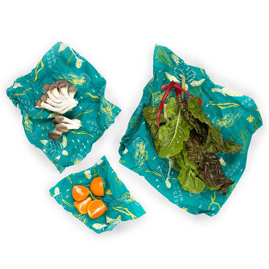 Set of teal reusable food wraps with vegetables on a white background