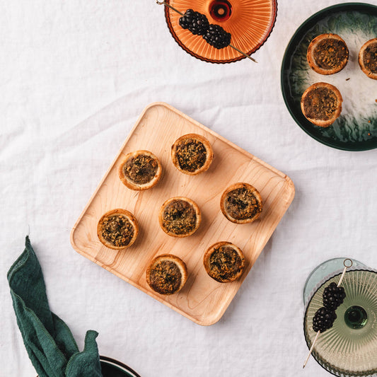 JK Adams Maple Appetizer Plate, 7"x7" with appetizers on it. In the background cocktails with blackberries.
