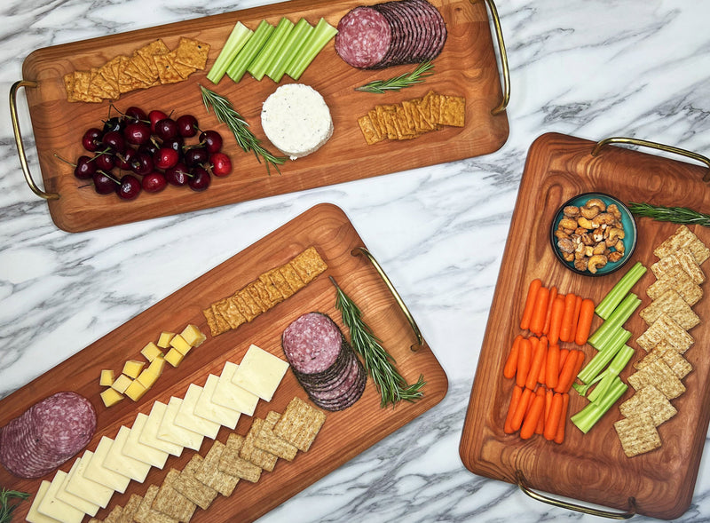 Three wooden cutting boards with assorted snacks on a marble surface