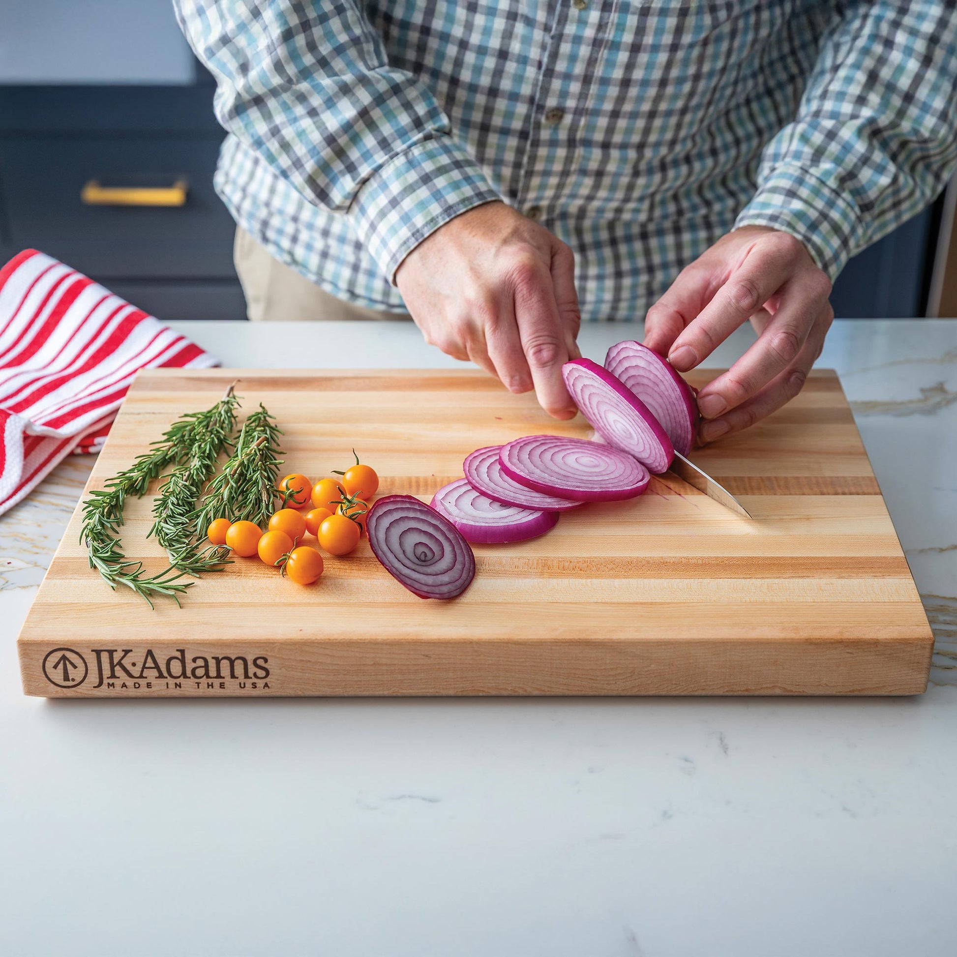 JK Adams Professional Edge Cutting board with sliced onions, tomatoes, and rosemary.