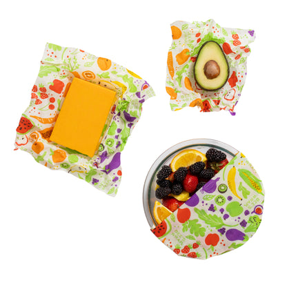 Reusable food wraps with fruits and vegetables pattern containing cheese, avocado, and berries on a white background