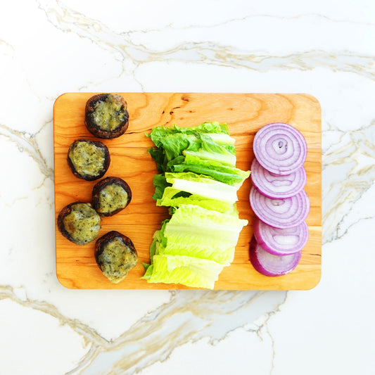 JK Adams 12"x9" Cherry Serving board lifestyle with stuffed mushrooms, lettuce and onions.
