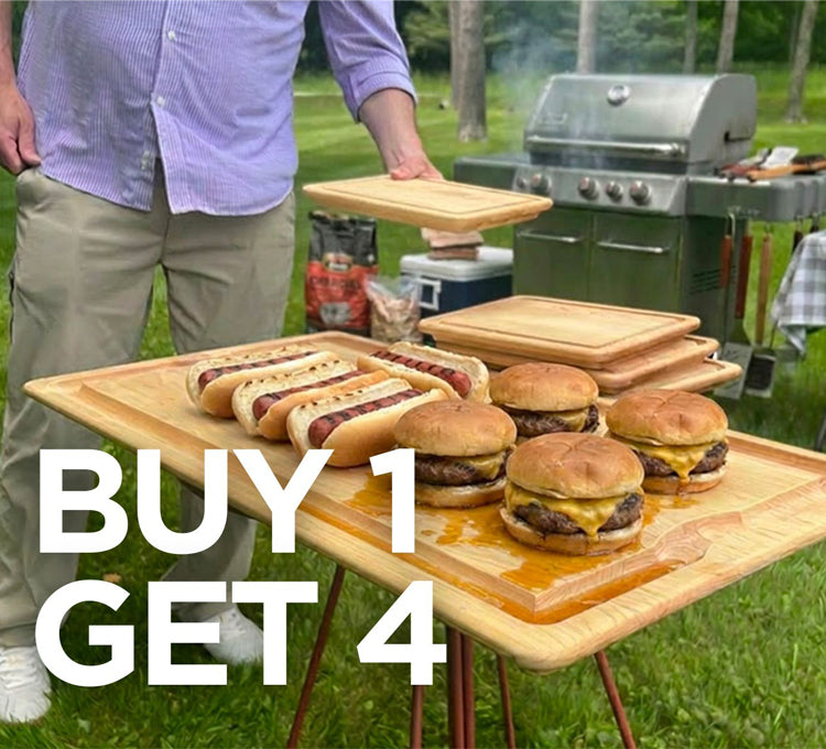 Person standing next to a table with burgers and hot dogs outdoors, with a grill and condiments in the background.