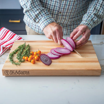 JK Adams Professional Edge Cutting board with sliced onions, tomatoes, and rosemary.
