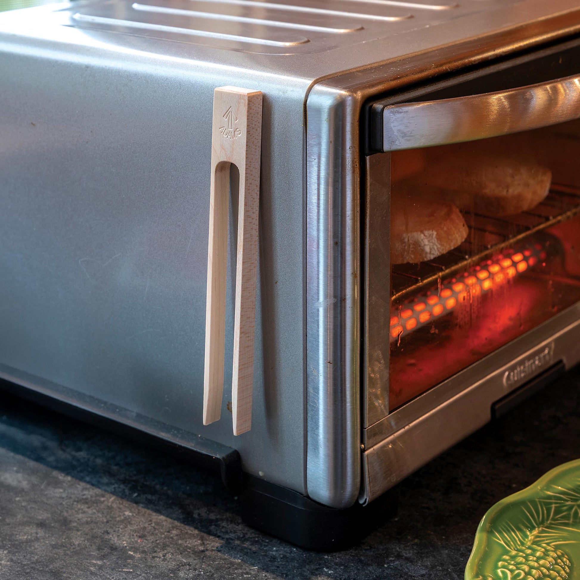 Silver toaster oven with bread inside on a dark surface