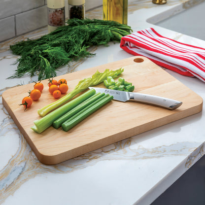 Wooden cutting board with celery, knife, and small tomatoes on a kitchen counter.