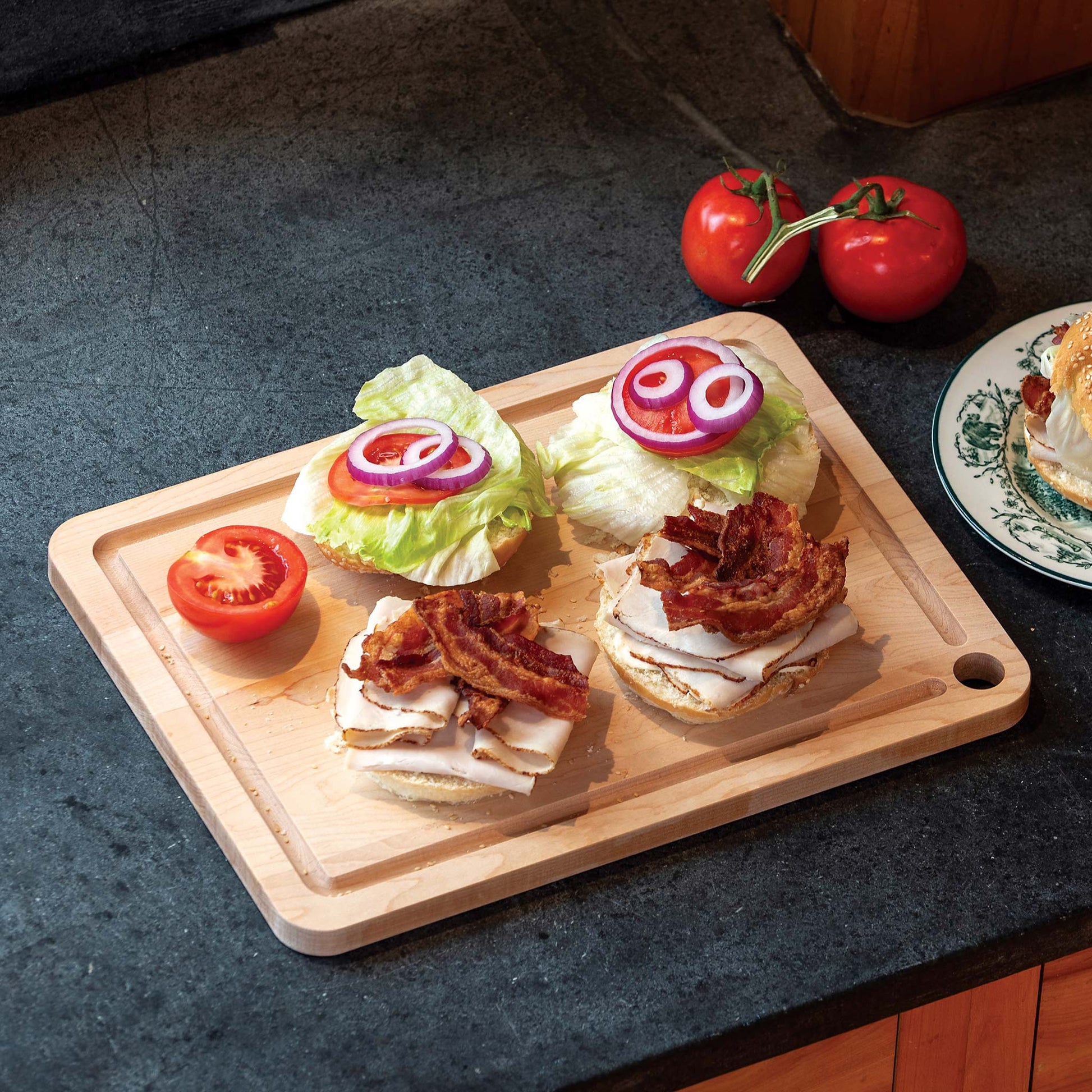 JK Adams Maple Prep cutting board with 2 sandwiches turkey, lettuce, tomato, red onions and bacon.