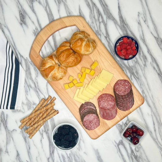 JK Adams Maple 1810 Cutting board lifestyle with croissants, cheese, charcutier on ample countertop.